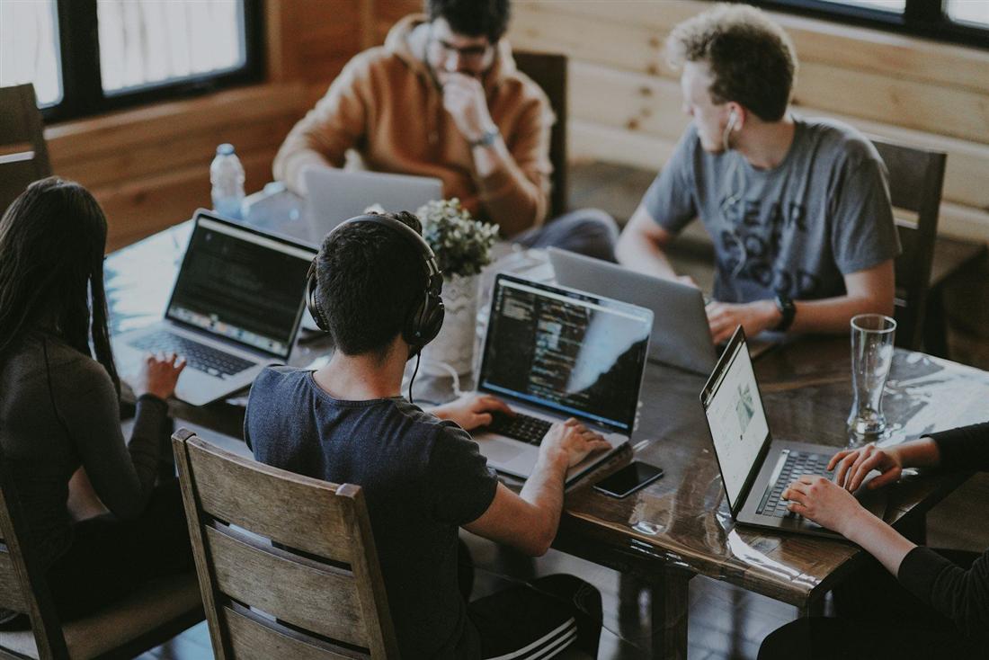 Un gruppo di lavoro al tavolo con i computer portatili